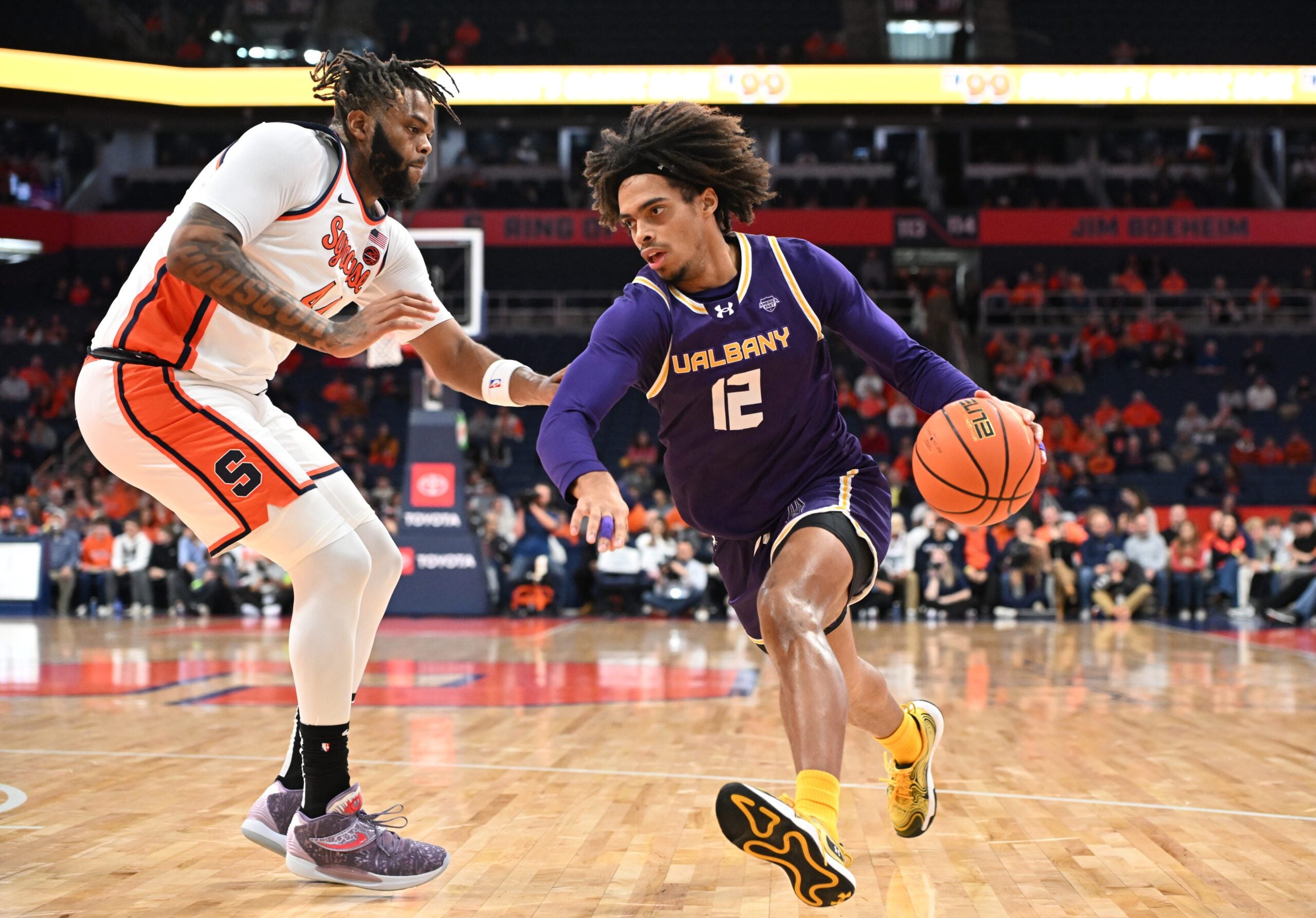 Dec 10, 2024; Syracuse, New York, USA; Albany Great Danes forward Justin Neely (12) drives the ball past Syracuse Orange center Eddie Lampkin Jr. (44) in the first half at the JMA Wireless Dome. Mandatory Credit: Mark Konezny-Imagn Images