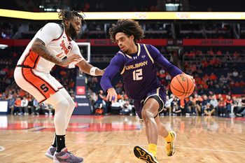 Dec 10, 2024; Syracuse, New York, USA; Albany Great Danes forward Justin Neely (12) drives the ball past Syracuse Orange center Eddie Lampkin Jr. (44) in the first half at the JMA Wireless Dome. Mandatory Credit: Mark Konezny-Imagn Images