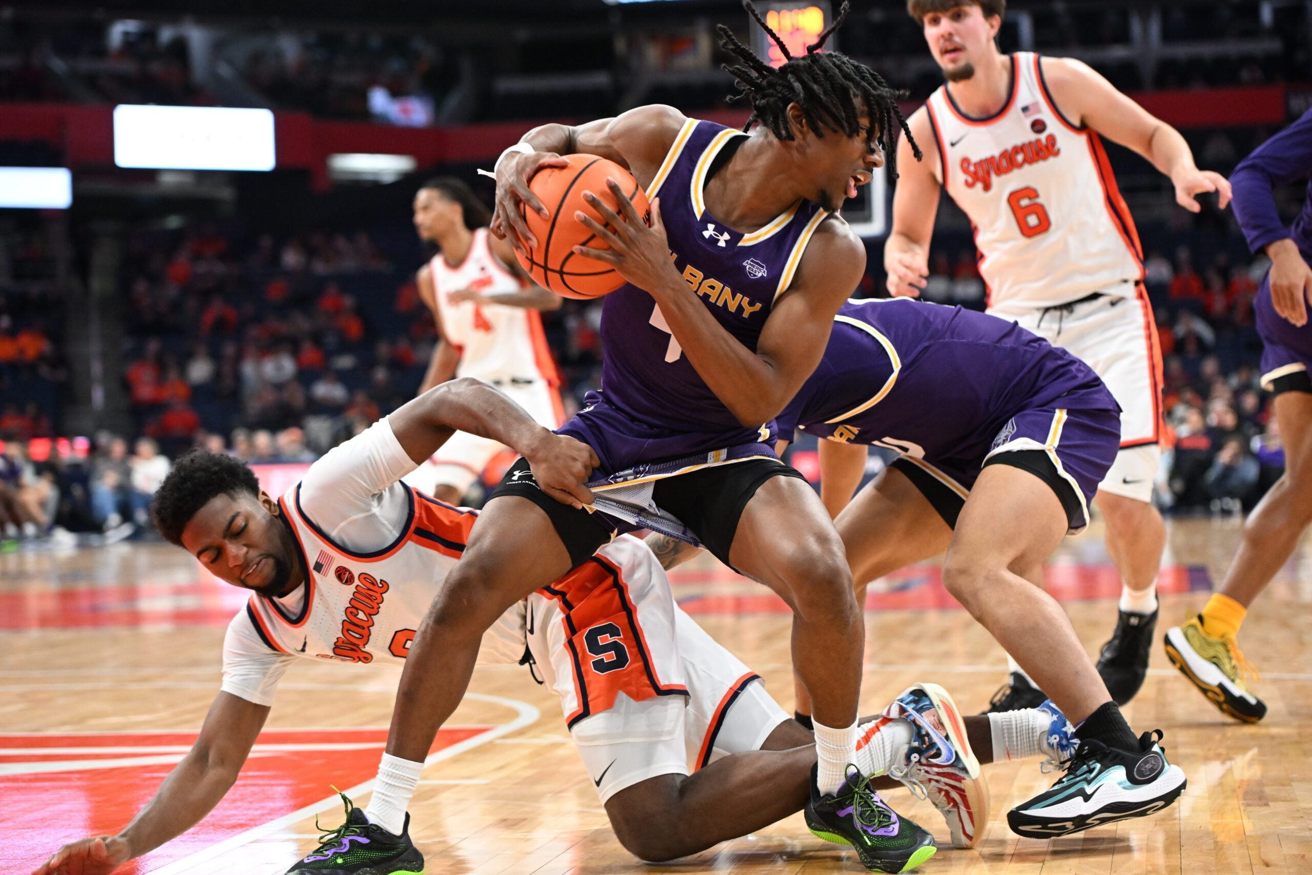 Dec 10, 2024; Syracuse, New York, USA; Albany Great Danes guard Amir Lindsey (4) is grabbed by Syracuse Orange guard Kyle Cuffe Jr. (0) after getting a rebound in the second half  at the JMA Wireless Dome. Mandatory Credit: Mark Konezny-Imagn Images