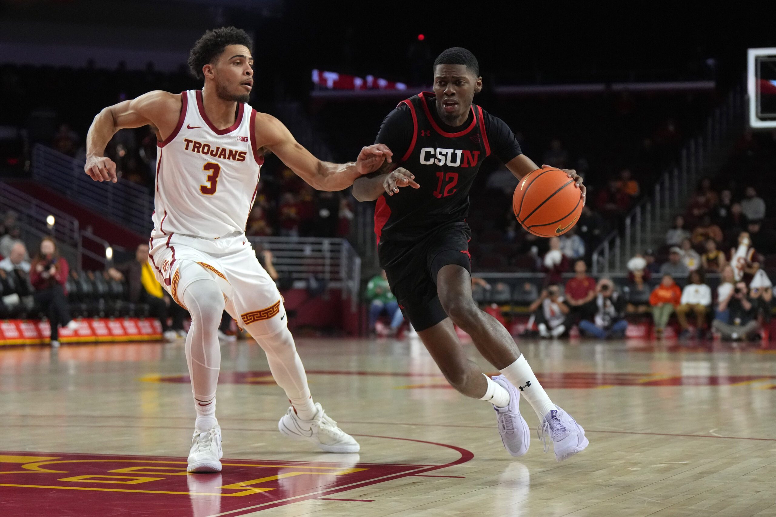 Dec 18, 2024; Los Angeles, California, USA; Cal State Northridge Matadors guard Scotty Washington (12) dribbles the ball against Southern California Trojans forward Matt Knowling (3) in the first half at Galen Center. Mandatory Credit: Kirby Lee-Imagn Images