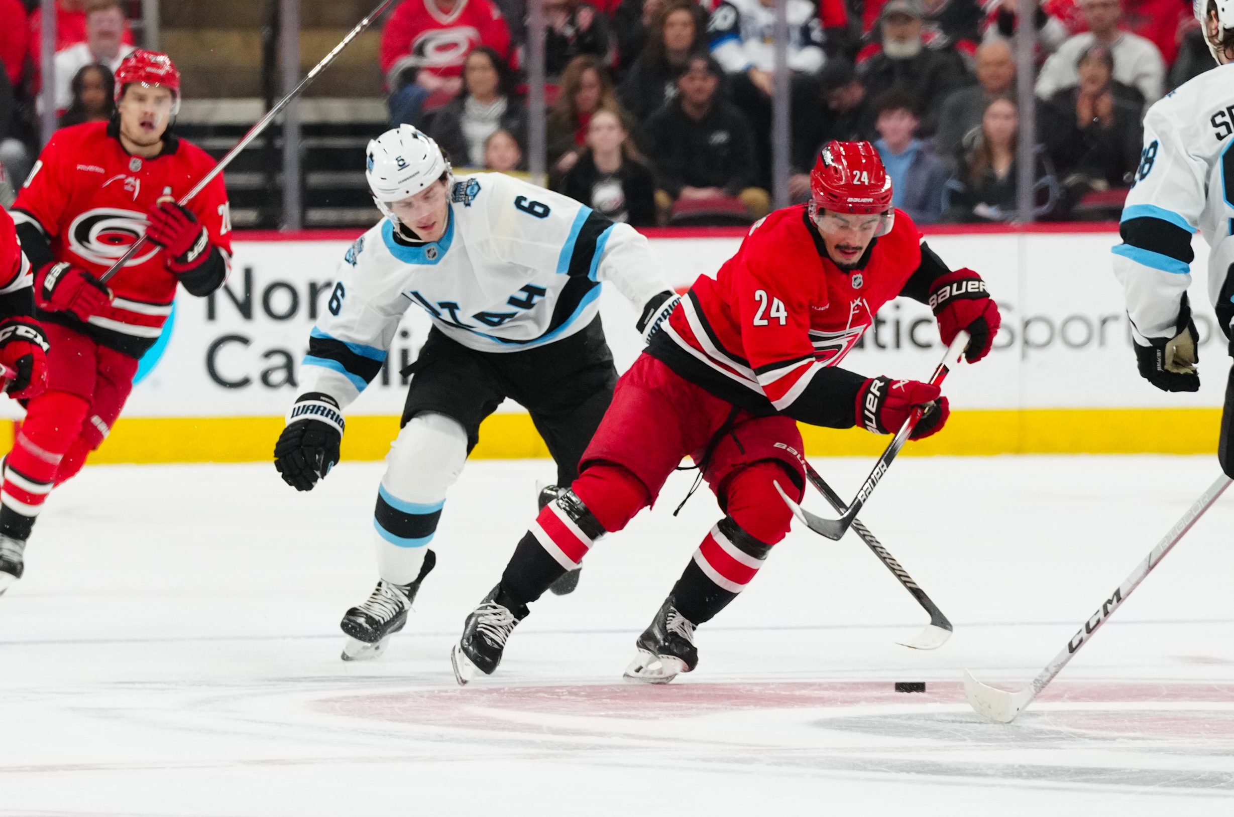 Feb 8, 2025; Raleigh, North Carolina, USA;  Carolina Hurricanes center Seth Jarvis (24) cuts past with the puck past Utah Hockey Club defenseman John Marino (6) during the third period at Lenovo Center. Mandatory Credit: James Guillory-Imagn Images