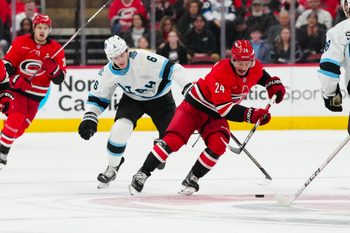 Feb 8, 2025; Raleigh, North Carolina, USA;  Carolina Hurricanes center Seth Jarvis (24) cuts past with the puck past Utah Hockey Club defenseman John Marino (6) during the third period at Lenovo Center. Mandatory Credit: James Guillory-Imagn Images