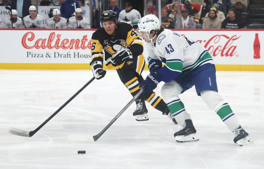 Oct 21, 2025; Pittsburgh, Pennsylvania, USA; Vancouver Canucks defenseman Quinn Hughes (43) moves the puck against Pittsburgh Penguins center Blake Lizotte (46) during the third period at PPG Paints Arena. Mandatory Credit: Charles LeClaire-Imagn Images