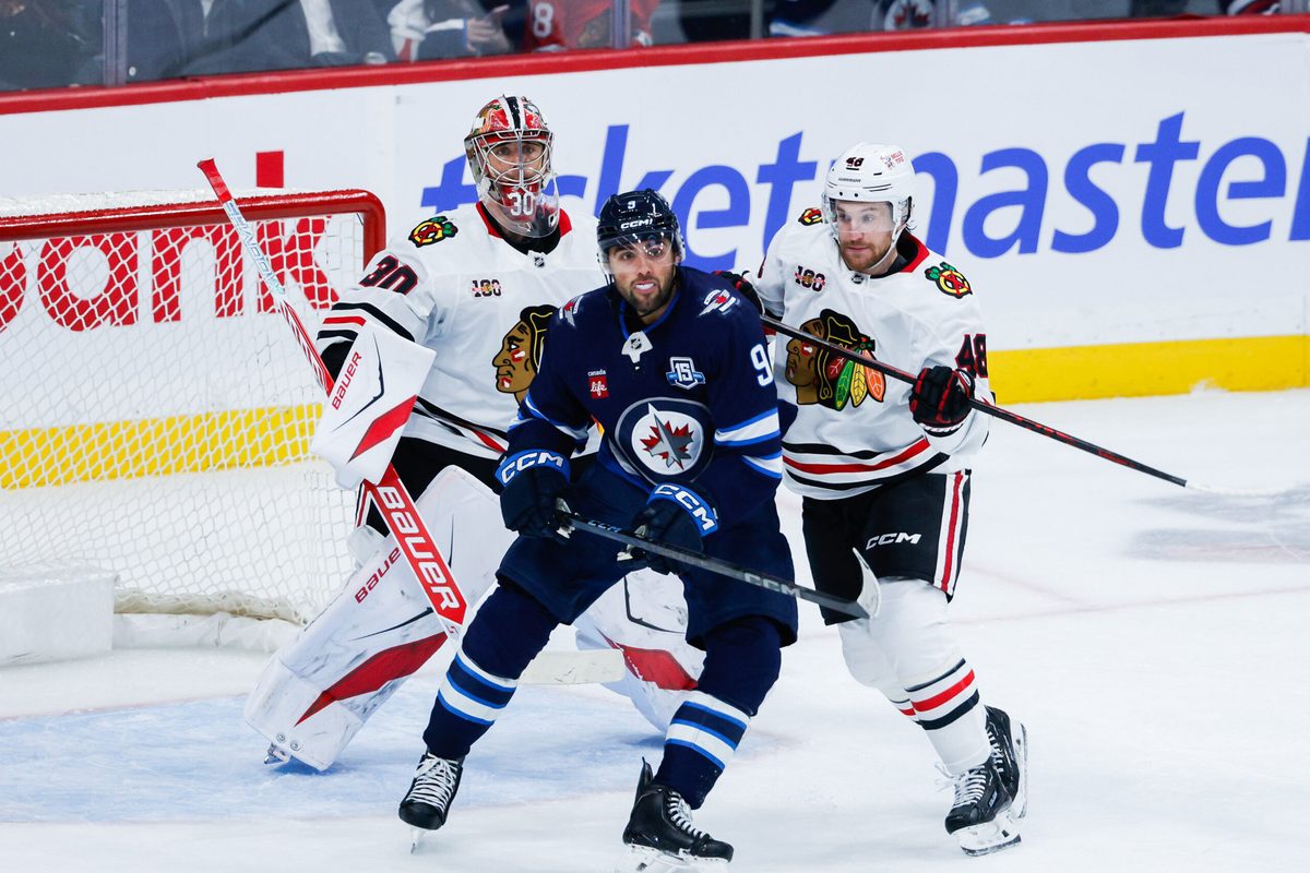 Oct 30, 2025; Winnipeg, Manitoba, CAN; Winnipeg Jets forward Alex Iafallo (9) jostles for position with Chicago Blackhawks defenseman Matt Grzelcyk (48) in front of Chicago Blackhawks goalie Spencer Knight (30) during the third period at Canada Life Centre. Mandatory Credit: Terrence Lee-Imagn Images
