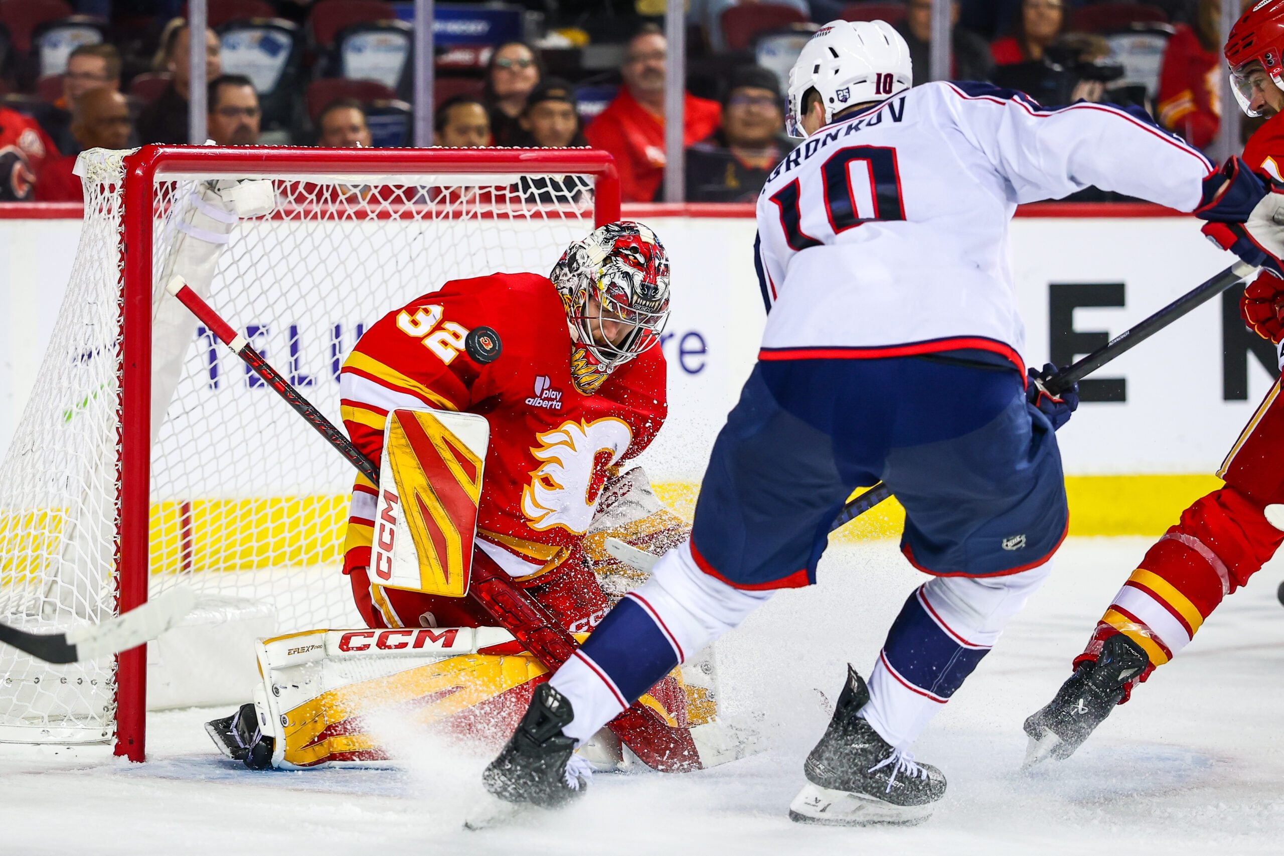 Nov 5, 2025; Calgary, Alberta, CAN; Calgary Flames goaltender Dustin Wolf (32) makes a save against Columbus Blue Jackets left wing Dmitri Voronkov (10) during the third period at Scotiabank Saddledome. Mandatory Credit: Sergei Belski-Imagn Images