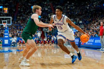 Nov 3, 2025; Lawrence, Kansas, USA; Kansas Jayhawks forward Bryson Tiller (15) drives against Green Bay Phoenix guard Keegan van Kauwenberg (3) during the second half at Allen Fieldhouse. Mandatory Credit: Jay Biggerstaff-Imagn Images