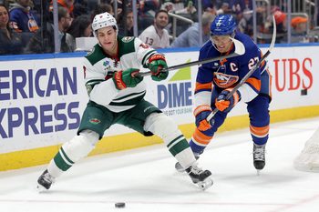 Nov 7, 2025; Elmont, New York, USA; Minnesota Wild defenseman Zeev Buium (8) fights for the puck against New York Islanders left wing Anders Lee (27) during the first period at UBS Arena. Mandatory Credit: Brad Penner-Imagn Images