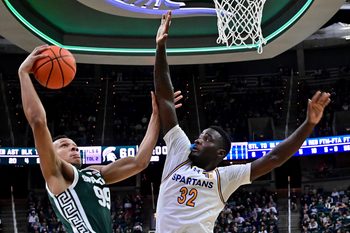 Nov 13, 2025; East Lansing, Michigan, USA;  Michigan State Spartans guard Divine Ugochukwu (99) tries to keep San Jose State Spartans forward Yaphet Moundi (32) away from his shot during the second half at Jack Breslin Student Events Center. Mandatory Credit: Dale Young-Imagn Images
