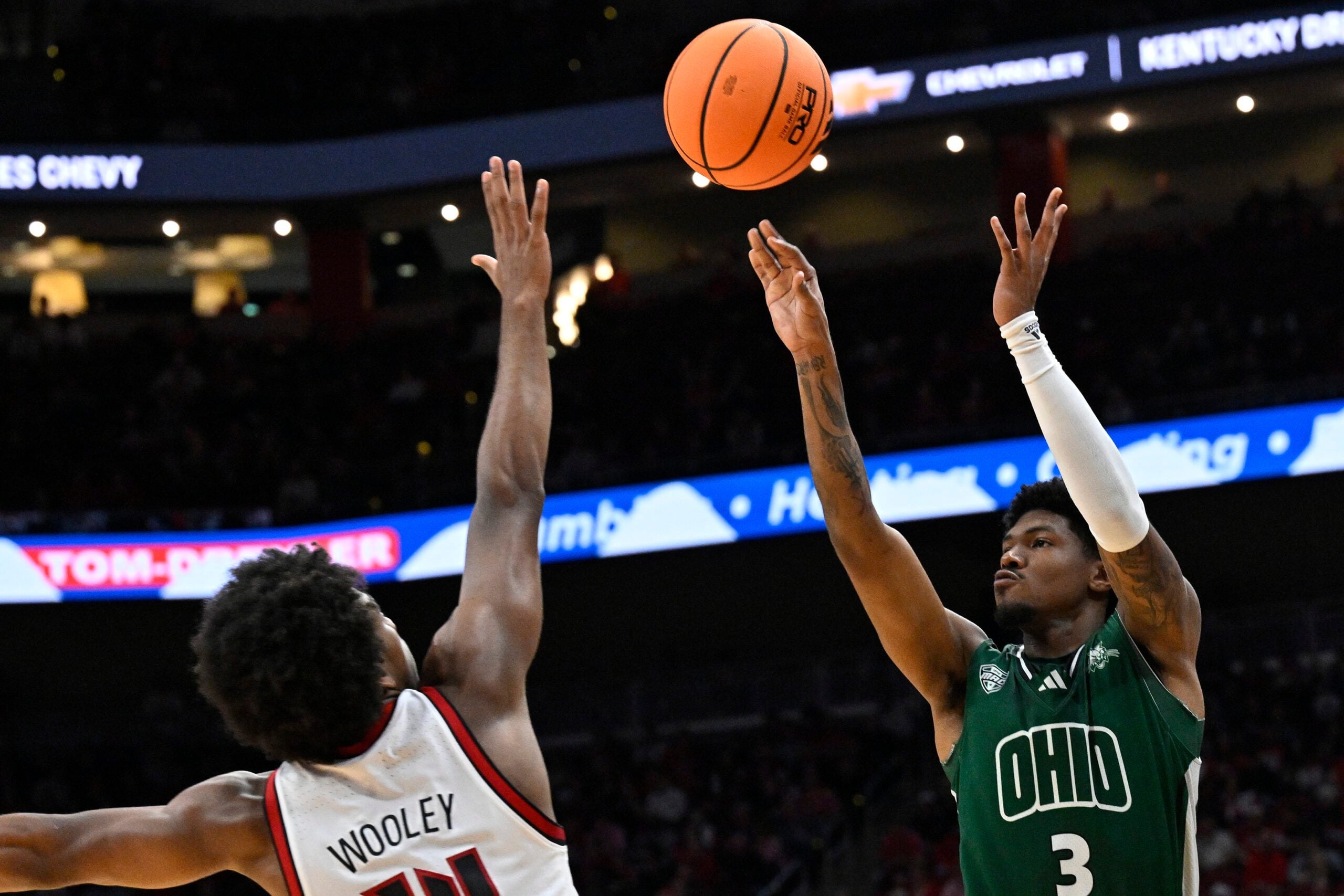 Nov 15, 2025; Louisville, Kentucky, USA;  Ohio Bobcats guard Dior Conners (3) shoots against Louisville Cardinals guard Adrian Wooley (14) during the first half at KFC Yum! Center. Mandatory Credit: Jamie Rhodes-Imagn Images