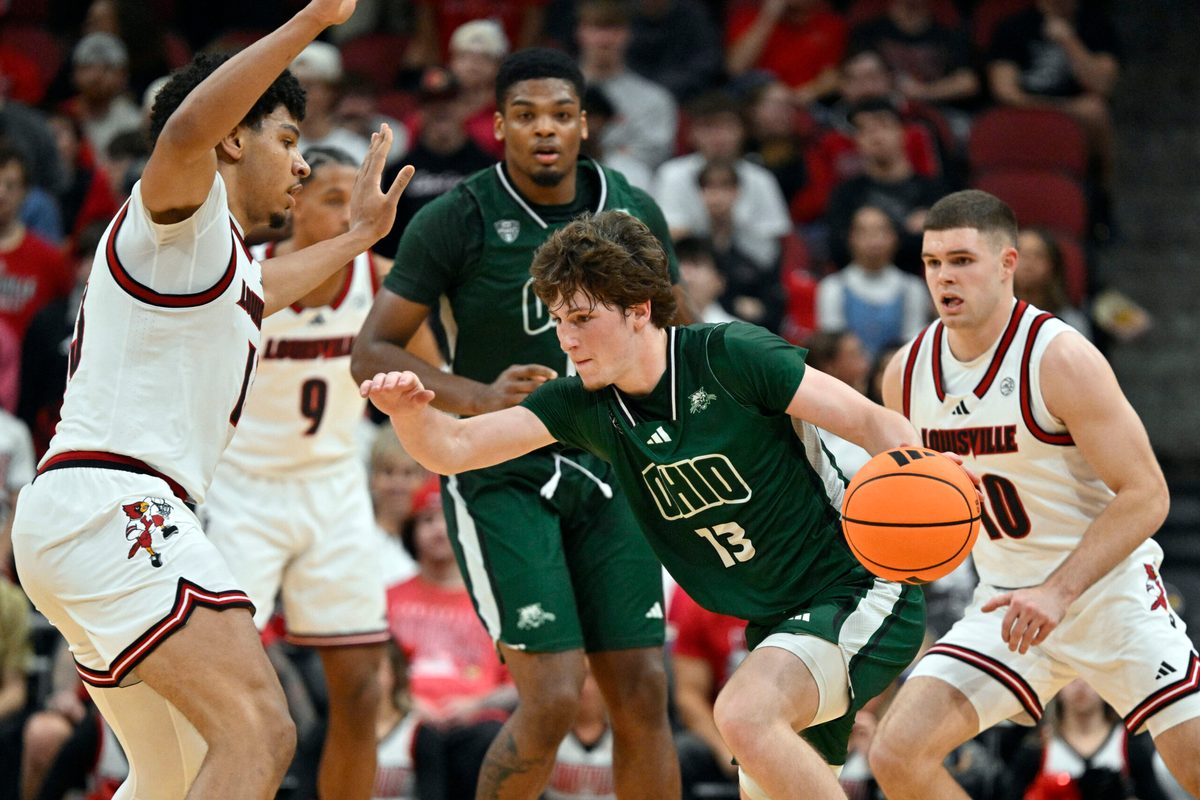 Nov 15, 2025; Louisville, Kentucky, USA; Ohio Bobcats guard Jackson Paveletzke (13) dribbles against Louisville Cardinals forward Sananda Fru (13) during the second half at KFC Yum! Center. Louisville defeated Ohio 106-81. Mandatory Credit: Jamie Rhodes-Imagn Images