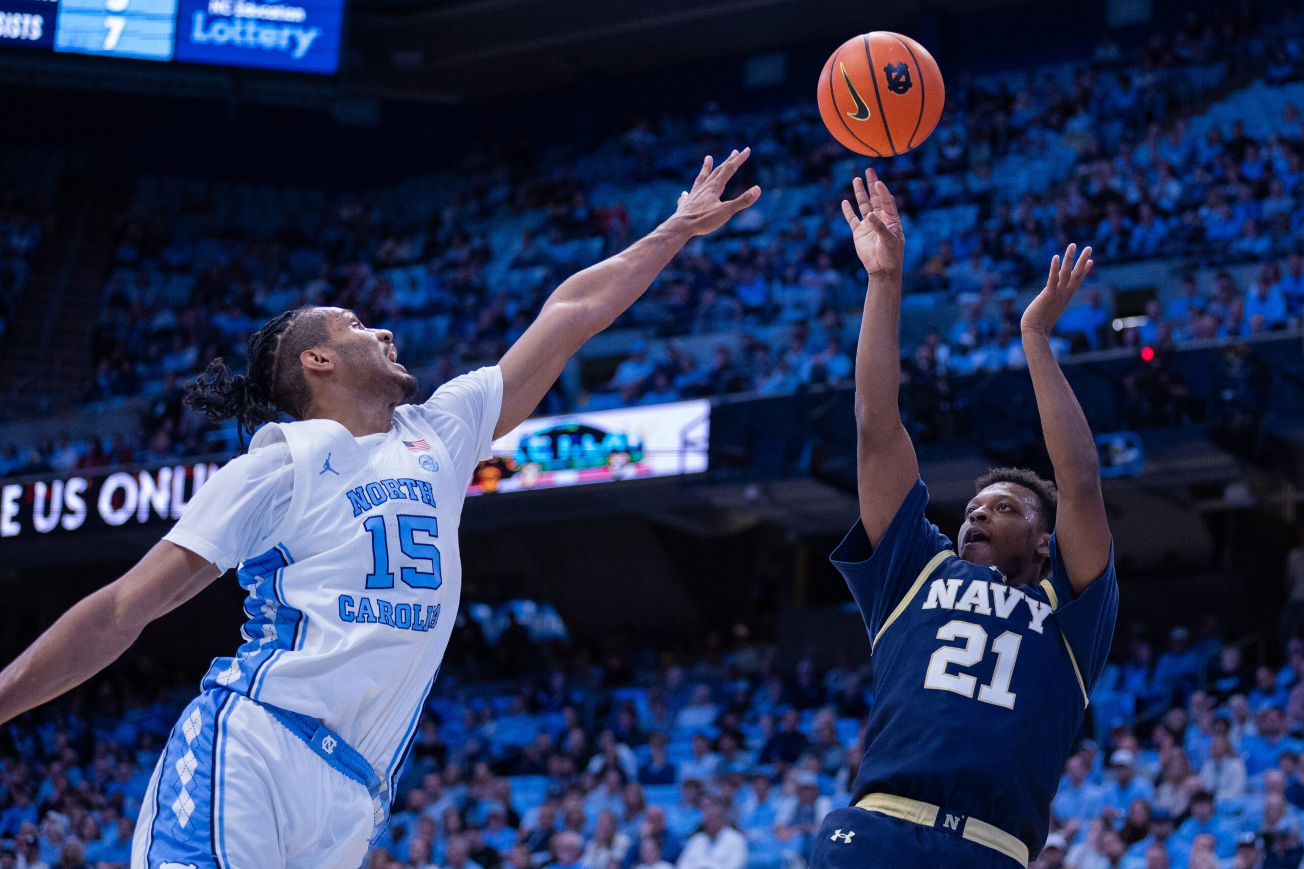 Nov 18, 2025; Chapel Hill, North Carolina, USA; Navy Midshipmen guard Jordan Pennick (21) shoots over North Carolina Tar Heels forward Jarin Stevenson (15) during the first half at Dean E. Smith Center. Mandatory Credit: Scott Kinser-Imagn Images