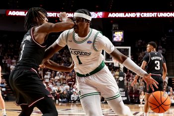 Nov 21, 2025; College Station, Texas, USA; Manhattan Jaspers forward Anthony Isaac (1) dribbles the ball as Texas A&M Aggies guard Josh Holloway (1) defends during the second half at Reed Arena. Mandatory Credit: Maria Lysaker-Imagn Images