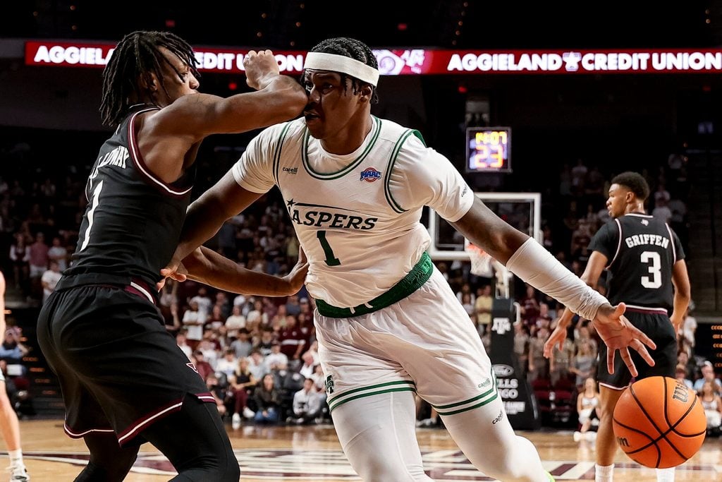 Nov 21, 2025; College Station, Texas, USA; Manhattan Jaspers forward Anthony Isaac (1) dribbles the ball as Texas A&M Aggies guard Josh Holloway (1) defends during the second half at Reed Arena. Mandatory Credit: Maria Lysaker-Imagn Images