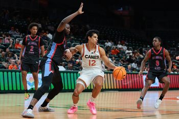 Nov 23, 2025; Coral Gables, Florida, USA; Miami Hurricanes guard Ii John Laboy (12) drives to the basket against Delaware State Hornets center Muazibini Adamu (35) during the second half at Watsco Center. Mandatory Credit: Sam Navarro-Imagn Images