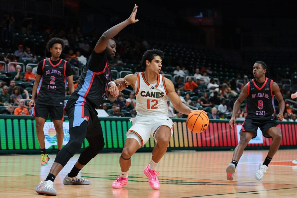 Nov 23, 2025; Coral Gables, Florida, USA; Miami Hurricanes guard Ii John Laboy (12) drives to the basket against Delaware State Hornets center Muazibini Adamu (35) during the second half at Watsco Center. Mandatory Credit: Sam Navarro-Imagn Images