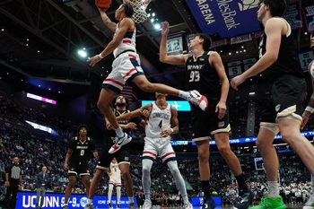 Nov 23, 2025; Hartford, Connecticut, USA; UConn Huskies forward Jayden Ross (23) makes the basket against Bryant Bulldogs guard Timofei Rudovskii (99) in the second half at Peoples Bank Arena. Mandatory Credit: David Butler II-Imagn Images
