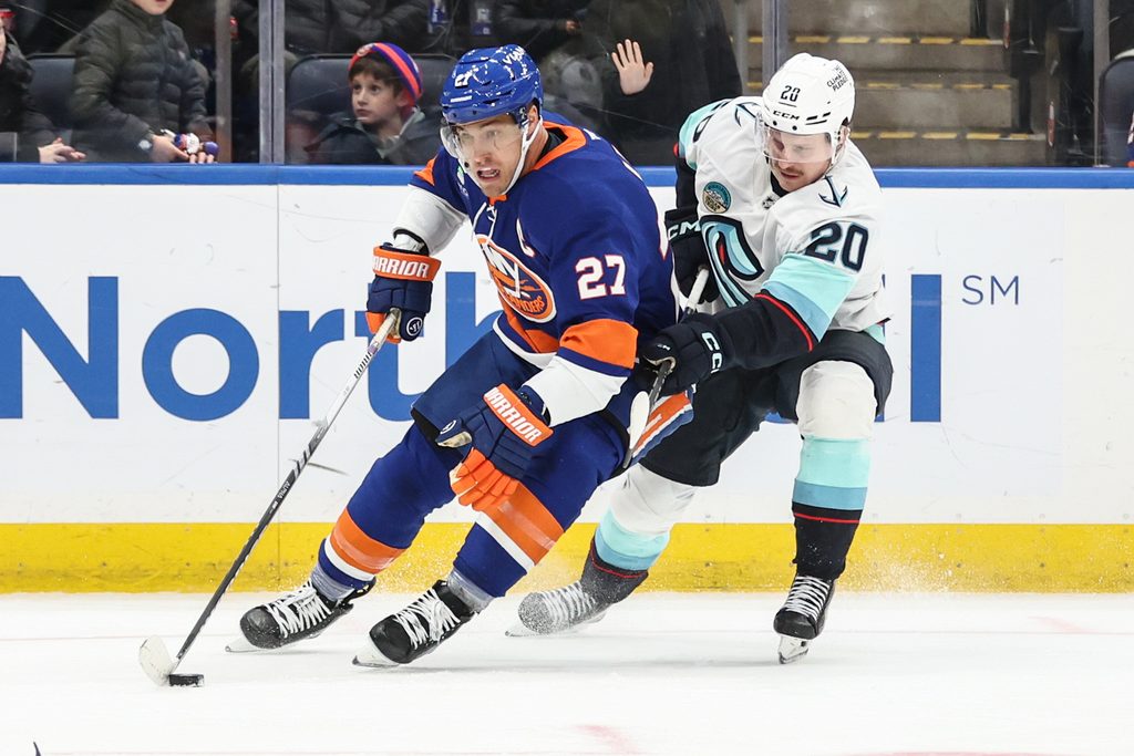 Nov 23, 2025; Elmont, New York, USA; New York Islanders left wing Anders Lee (27) and Seattle Kraken right wing Eeli Tolvanen (20) battle for control of the puck in the third period at UBS Arena. Mandatory Credit: Wendell Cruz-Imagn Images
