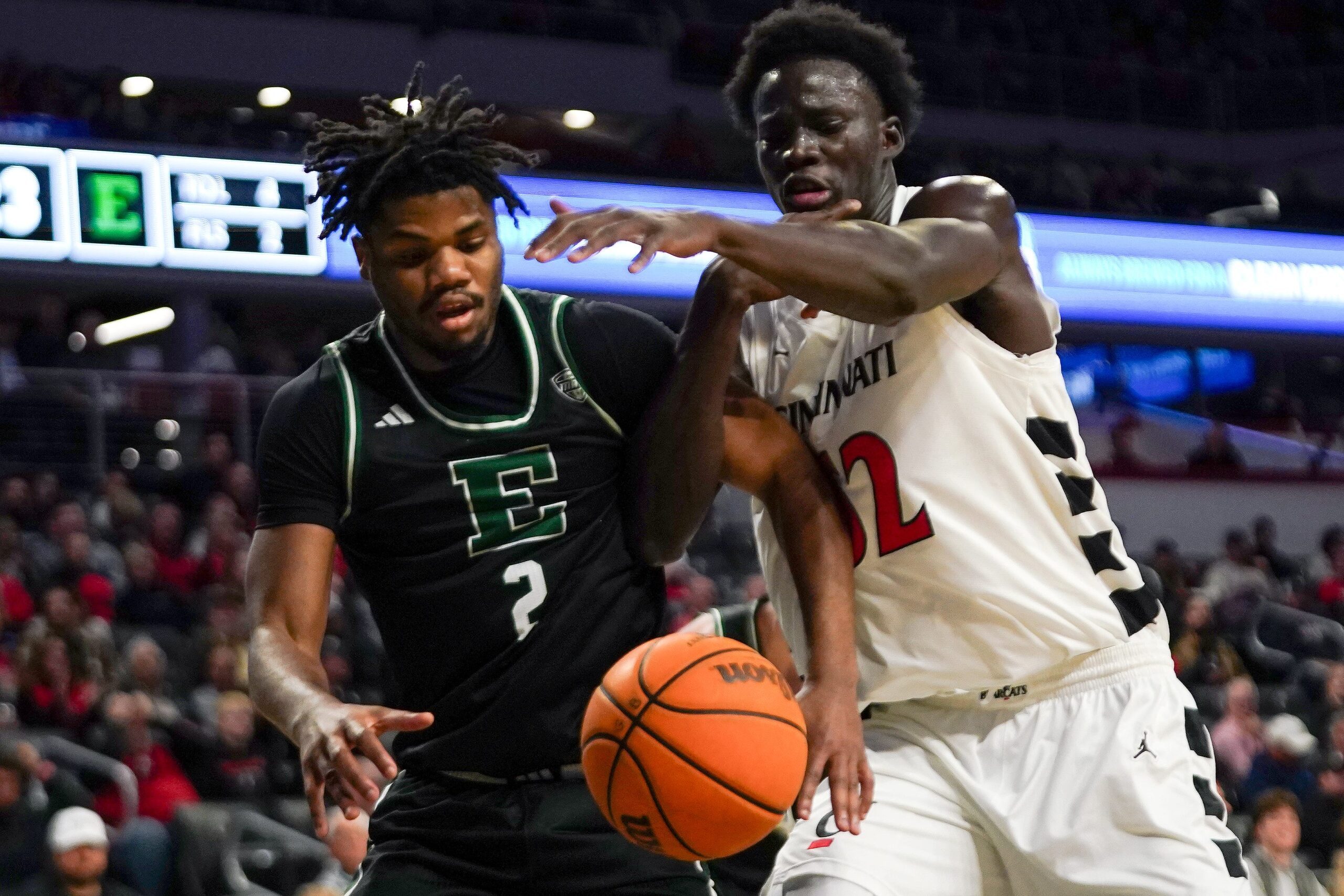 Eastern Michigan Eagles guard Carlos Hart (2) and Cincinnati Bearcats center Moustapha Thiam (52) reach out for a rebound in the first half of a NCAA men’s basketball game between the Cincinnati Bearcats and Eastern Michigan Eagles, Wednesday, Nov. 26, 2025, at Fifth Third Arena in Cincinnati.