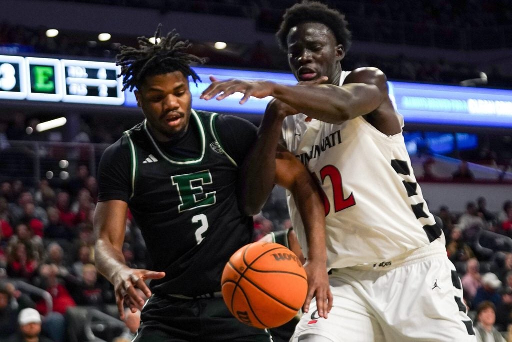 Eastern Michigan Eagles guard Carlos Hart (2) and Cincinnati Bearcats center Moustapha Thiam (52) reach out for a rebound in the first half of a NCAA men’s basketball game between the Cincinnati Bearcats and Eastern Michigan Eagles, Wednesday, Nov. 26, 2025, at Fifth Third Arena in Cincinnati.