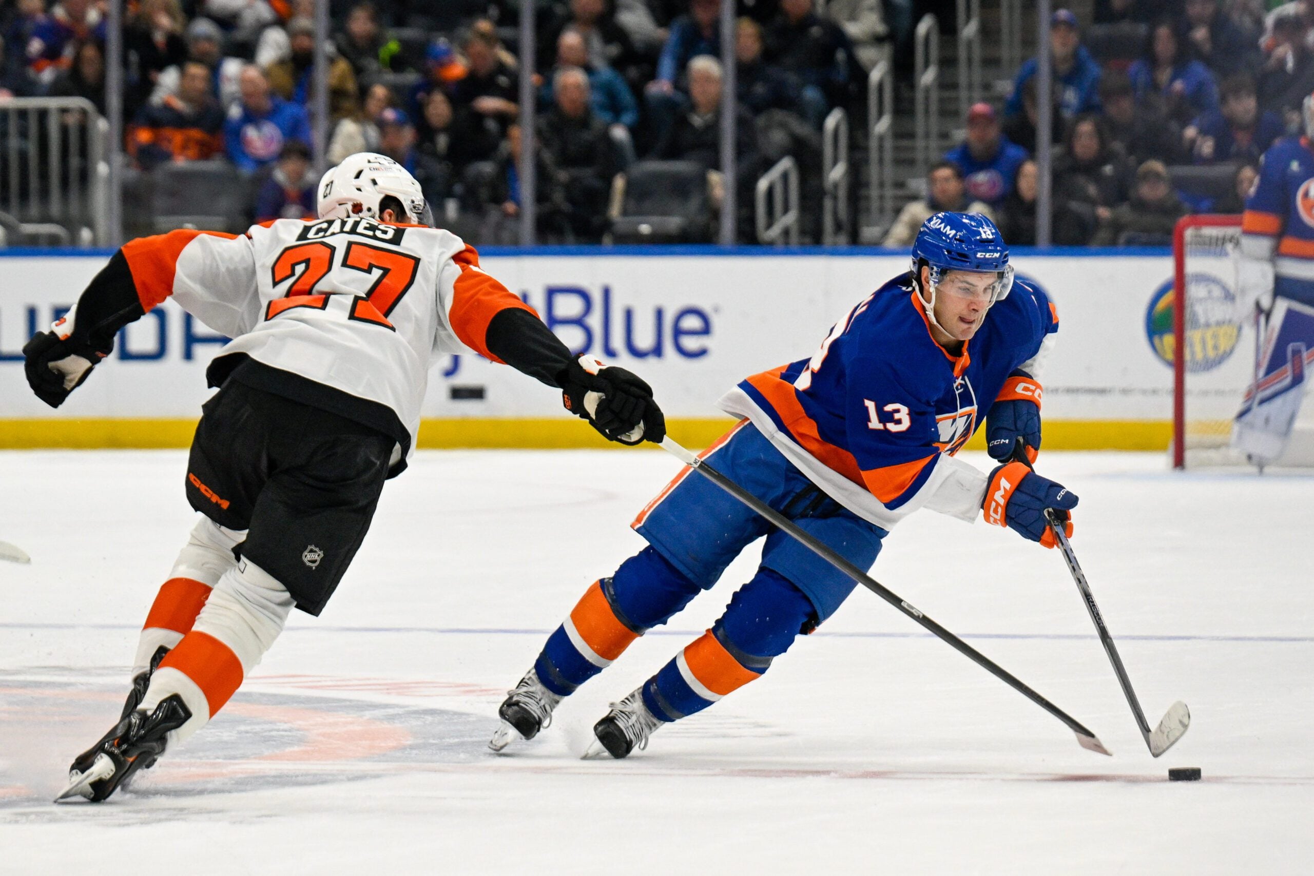 Nov 28, 2025; Elmont, New York, USA; New York Islanders center Mathew Barzal (13) skates with the puck defended by Philadelphia Flyers left wing Noah Cates (27) during the second period at UBS Arena. Mandatory Credit: Dennis Schneidler-Imagn Images