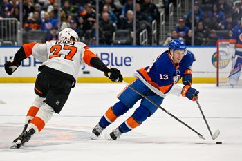Nov 28, 2025; Elmont, New York, USA; New York Islanders center Mathew Barzal (13) skates with the puck defended by Philadelphia Flyers left wing Noah Cates (27) during the second period at UBS Arena. Mandatory Credit: Dennis Schneidler-Imagn Images