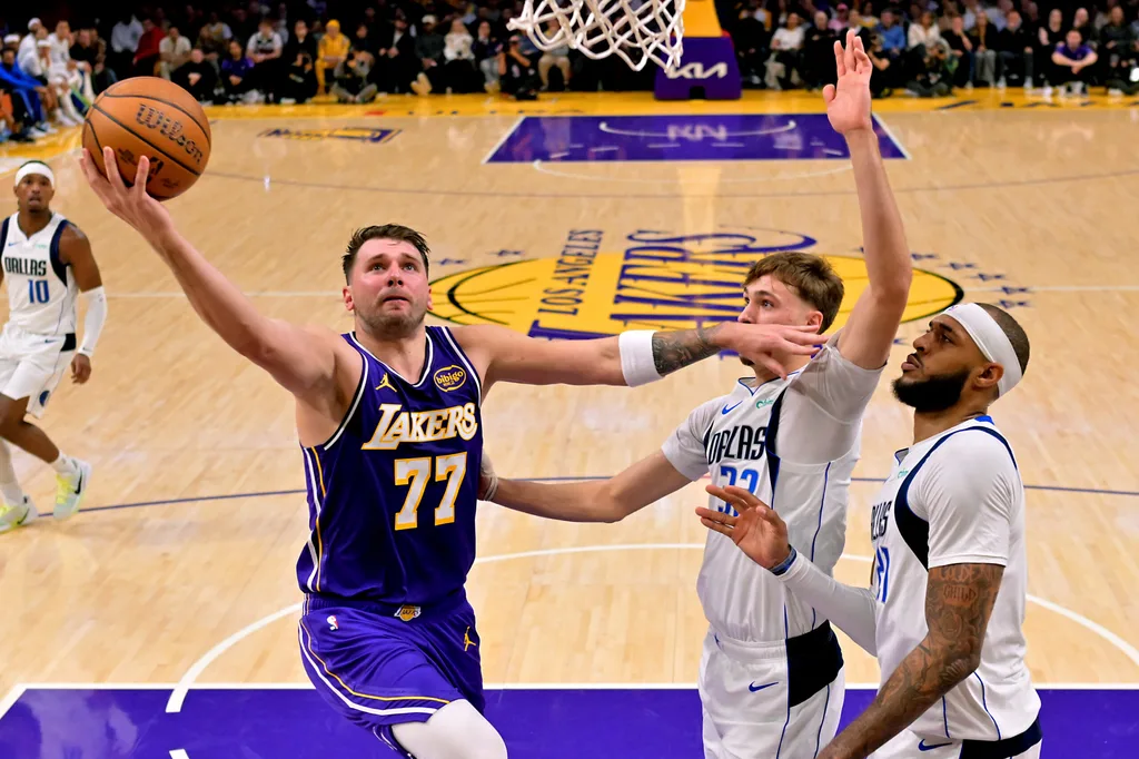 Nov 28, 2025; Los Angeles, California, USA; Los Angeles Lakers guard Luka Doncic (77) drives past Dallas Mavericks forward Cooper Flagg (32) and forward Daniel Gafford (21) in the first half at Crypto.com Arena. Mandatory Credit: Jayne Kamin-Oncea-Imagn Images
