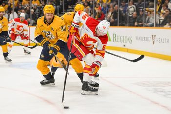 Dec 2, 2025; Nashville, Tennessee, USA;  Calgary Flames left wing Joel Farabee (86) and Nashville Predators center Ryan O'Reilly (90) battle for the puck during the second period at Bridgestone Arena. Mandatory Credit: Steve Roberts-Imagn Images