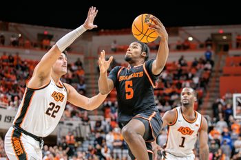 Dec 2, 2025; Stillwater, Oklahoma, USA; Sam Houston Bearkats guard Justin Begg (5) drives to the basket around Oklahoma State Cowboys center Parsa Fallah (22) during the second half at Gallagher-Iba Arena. Mandatory Credit: William Purnell-Imagn Images