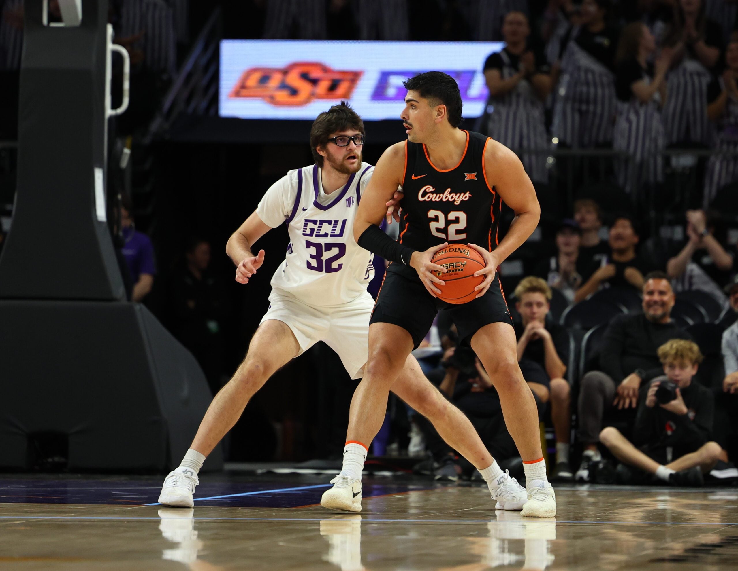 Dec 6, 2025; Phoenix, Arizona, USA;  Grand Canyon Lopes forward Wilhelm Breidenbach (32) plays defense on Oklahoma State Cowboys forward Parsa Fallah (22) at PHX Arena. Mandatory Credit: Anna Carrington-Imagn Images