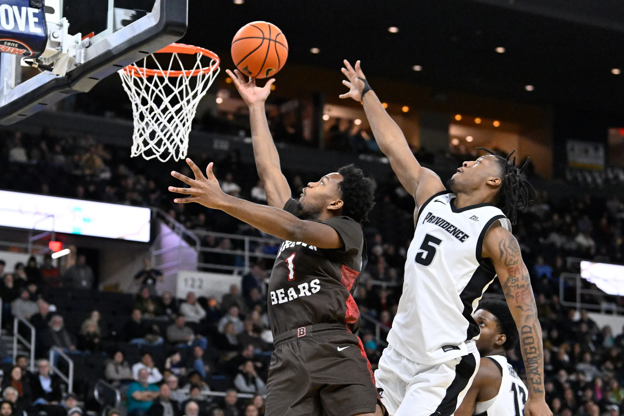 Dec 9, 2025; Providence, Rhode Island, USA; Brown Bears guard Isaiah Langham (1) shoots a layup through the defense of Providence Friars forward Jamier Jones (5) during the second half at Amica Mutual Pavilion. Mandatory Credit: Eric Canha-Imagn Images