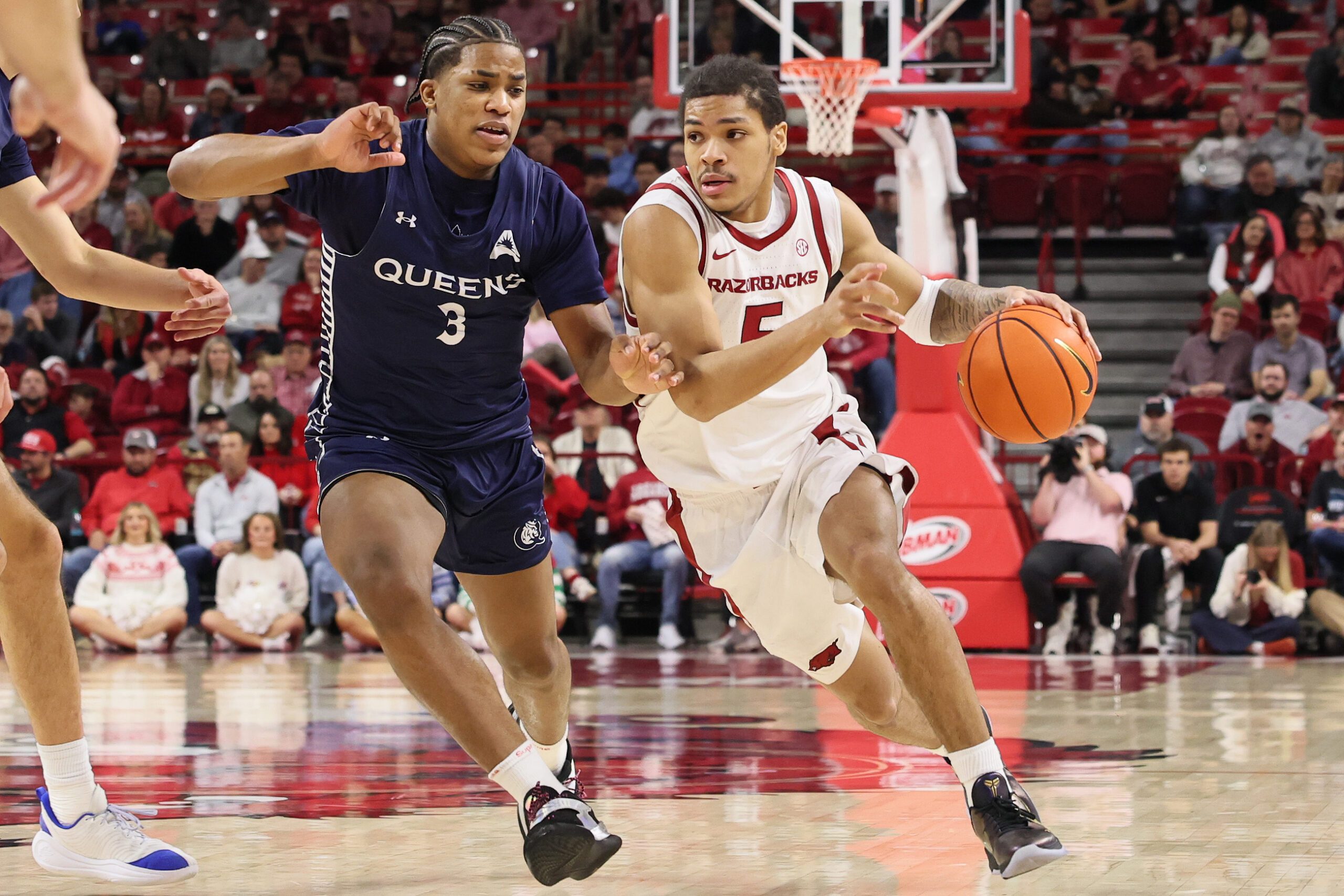 Dec 16, 2025; Fayetteville, Arkansas, USA; Arkansas Razorbacks guard Darius Acuff Jr (5) drives against Queens Royals Isaiah Henry (3) during the second half at Bud Walton Arena. Arkansas won 108-80. Mandatory Credit: Nelson Chenault-Imagn Images
