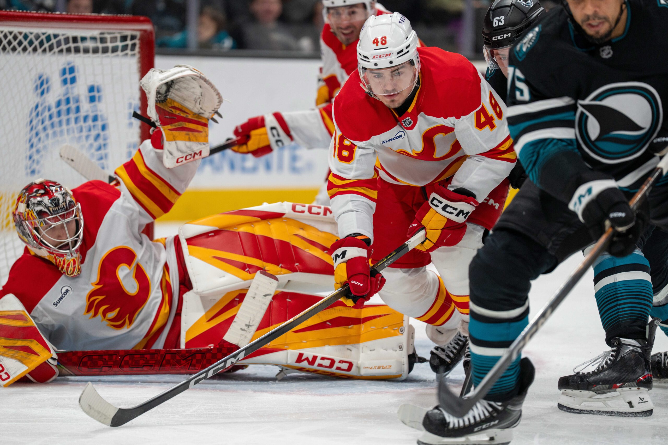 Dec 16, 2025; San Jose, California, USA; San Jose Sharks right wing Ryan Reaves (75) and Calgary Flames defenseman Hunter Brzustewicz (48) battle for position in front of the net during the second period at SAP Center at San Jose. Mandatory Credit: Neville E. Guard-Imagn Images