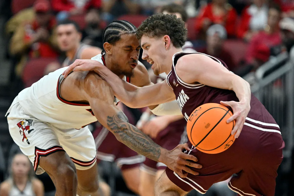 Dec 20, 2025; Louisville, Kentucky, USA; Montana Grizzlies guard Grant Kepley (11) dribbles under the pressure of Louisville Cardinals forward Khani Rooths (9) during the second half at KFC Yum! Center. Louisville defeated Montana 94-54. Mandatory Credit: Jamie Rhodes-Imagn Images