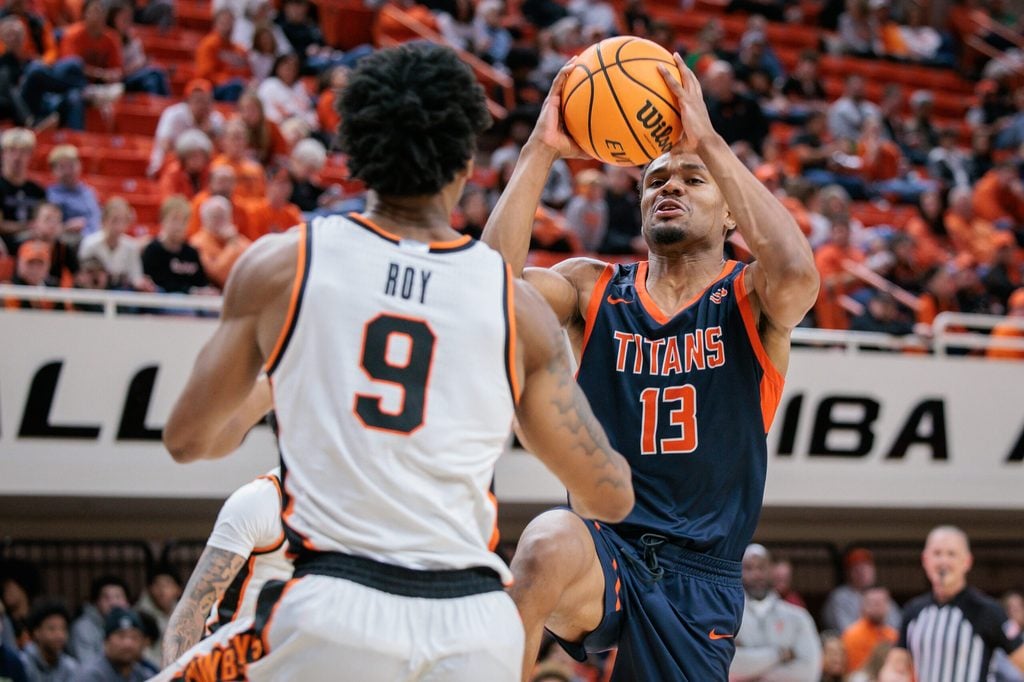 Dec 21, 2025; Stillwater, Oklahoma, USA; Cal State Fullerton Titans guard Jefferson de la Cruz Monegro (13) drives to the basket around Oklahoma State Cowboys guard Anthony Roy (9) during the second half at Gallagher-Iba Arena. Mandatory Credit: William Purnell-Imagn Images