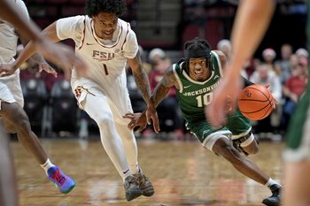 Dec 22, 2025; Tallahassee, Florida, USA; Jacksonville University Dolphins guard Simon Wheeler (1) drives the ball forward against Florida State Seminoles guard Martin Somerville (1) during the second half at Donald L. Tucker Center. Mandatory Credit: Melina Myers-Imagn Images