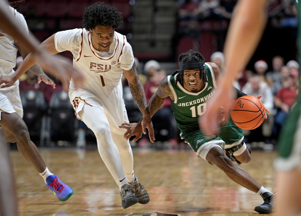 Dec 22, 2025; Tallahassee, Florida, USA; Jacksonville University Dolphins guard Simon Wheeler (1) drives the ball forward against Florida State Seminoles guard Martin Somerville (1) during the second half at Donald L. Tucker Center. Mandatory Credit: Melina Myers-Imagn Images