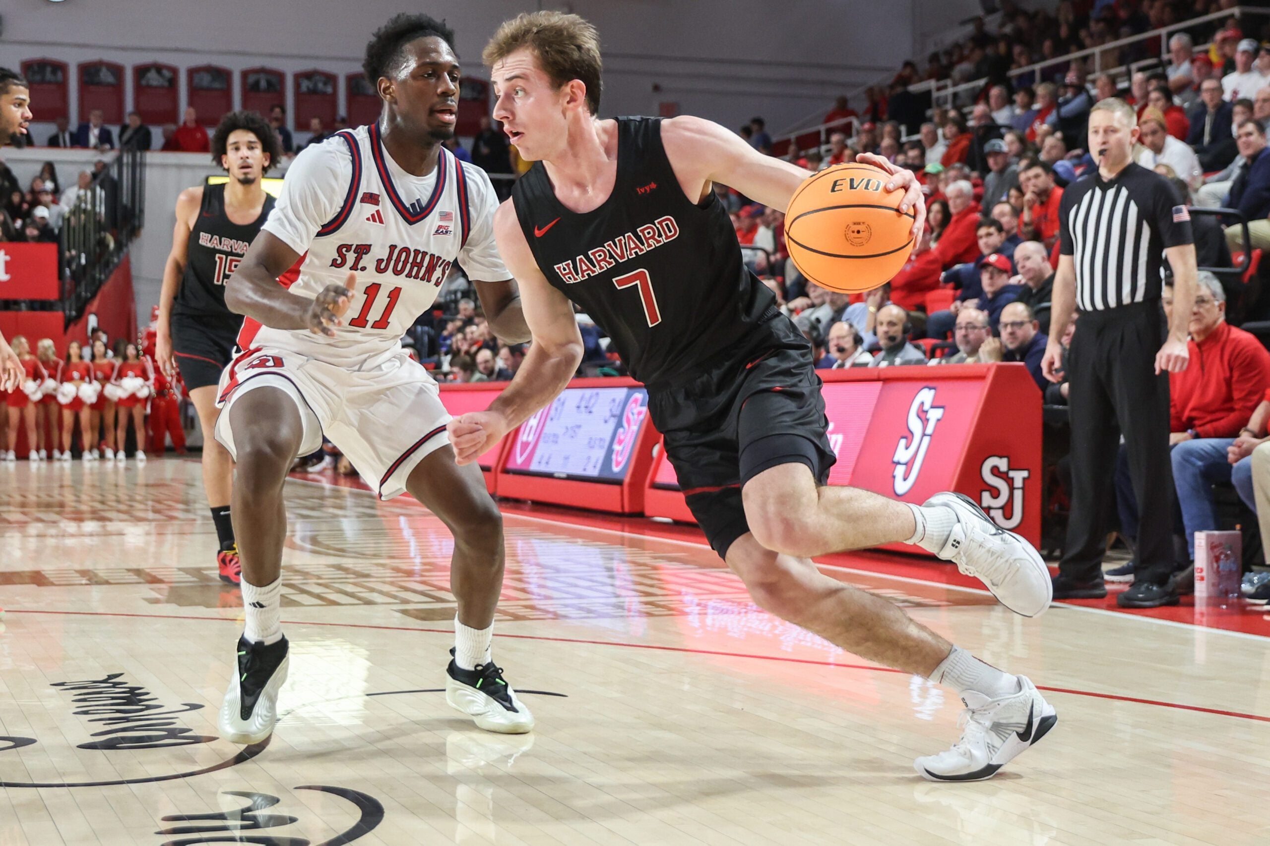 Dec 23, 2025; Queens, New York, USA;  Harvard Crimson guard Austin Hunt (7) drives past St. John's Red Storm guard Ian Jackson (11) in the first half at Carnesecca Arena. Mandatory Credit: Wendell Cruz-Imagn Images