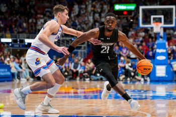 Dec 16, 2025; Lawrence, Kansas, USA; Towson Tigers guard Jack Doumbia Jr. (21) drives against Kansas Jayhawks guard Kohl Rosario (7) during the first half at Allen Fieldhouse. Mandatory Credit: Jay Biggerstaff-Imagn Images