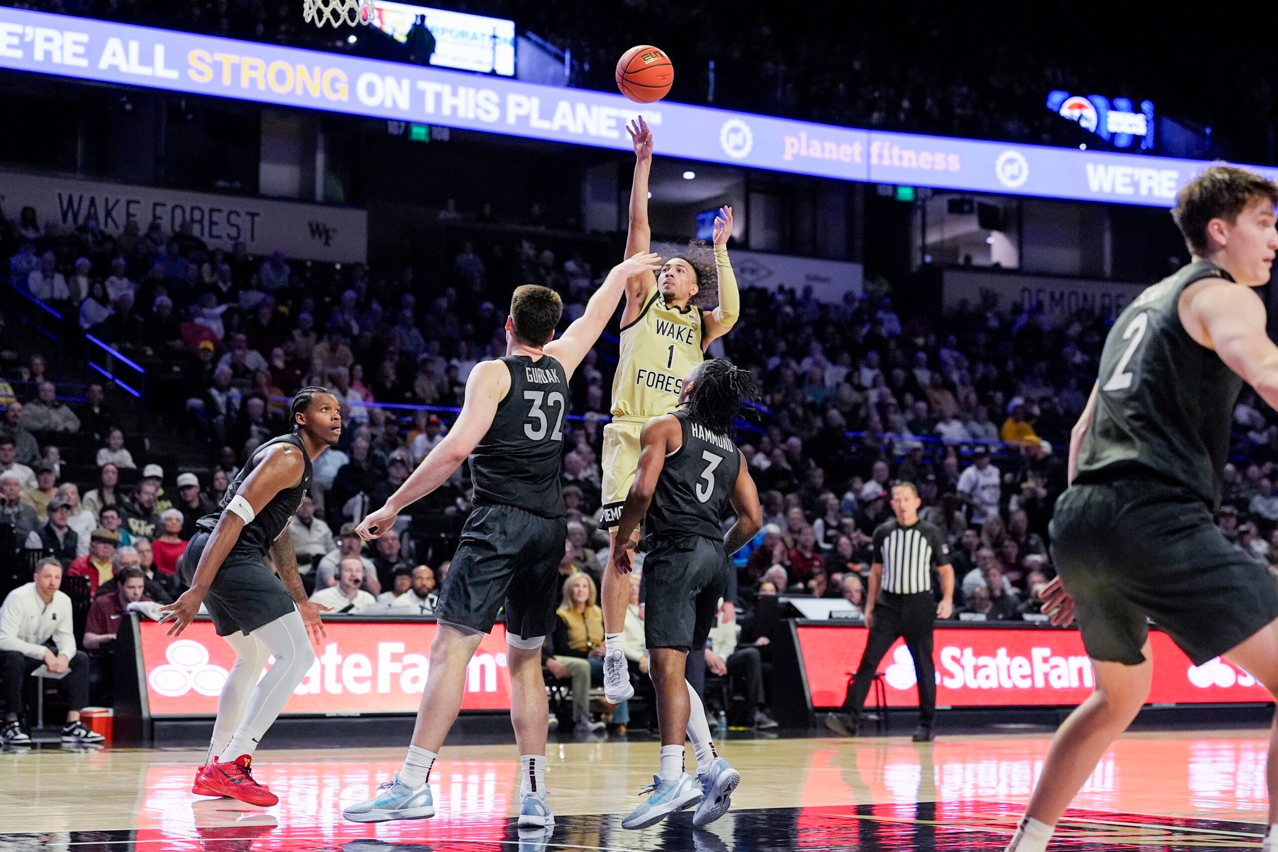 Jan 3, 2026; Winston-Salem, North Carolina, USA; Wake Forest Demon Deacons guard Nate Calmese (1) shoots the ball over Virginia Tech Hokies center Christian Gurdak (32) and guard Ben Hammond (3) during the first half at Lawrence Joel Veterans Memorial Coliseum. Mandatory Credit: Jim Dedmon-Imagn Images