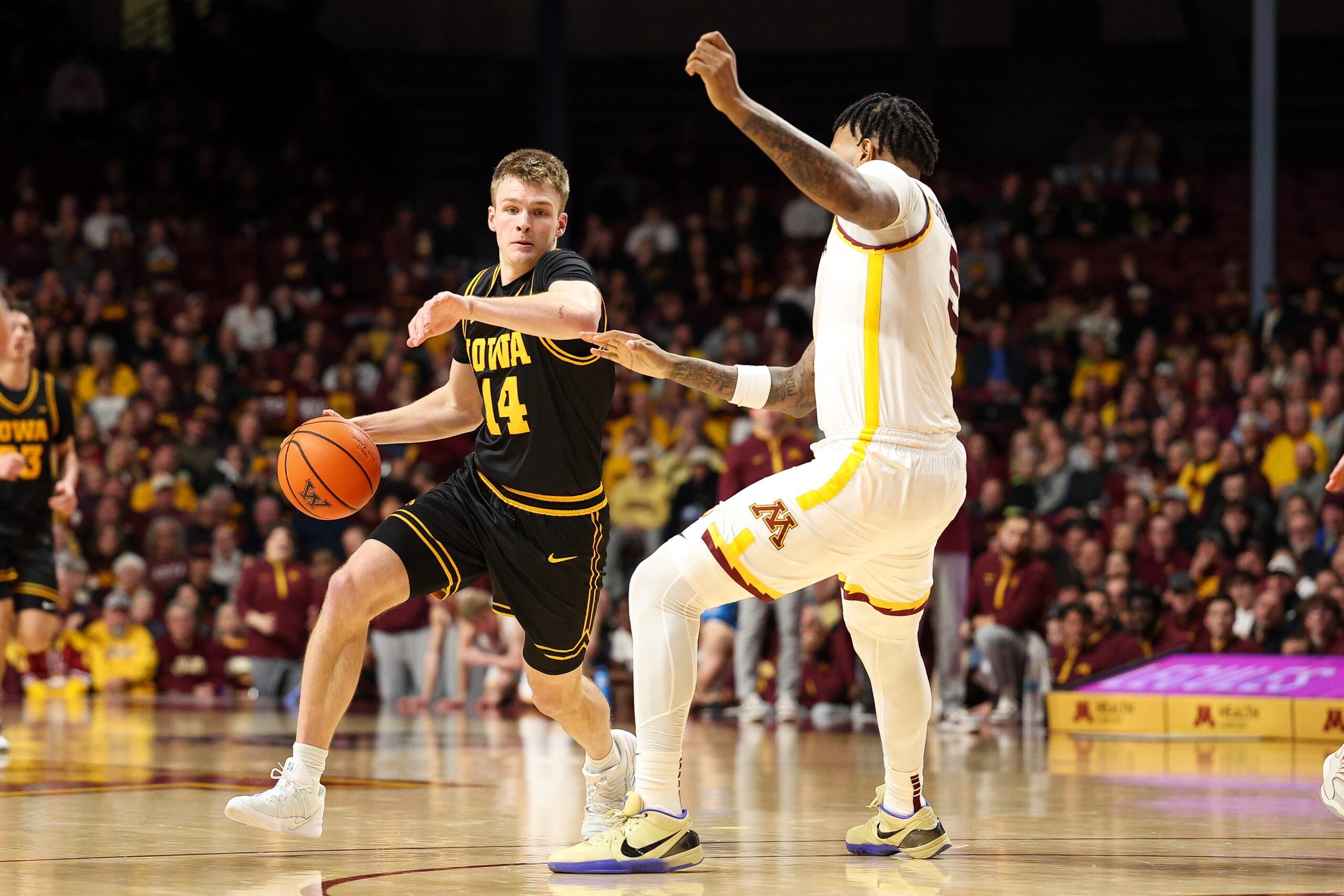 Jan 6, 2026; Minneapolis, Minnesota, USA; Iowa Hawkeyes guard Bennett Stirtz (14) works around Minnesota Golden Gophers forward Jaylen Crocker-Johnson (5) during the second half at Williams Arena. Mandatory Credit: Matt Krohn-Imagn Images