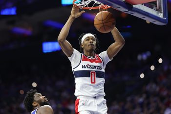 Jan 7, 2026; Philadelphia, Pennsylvania, USA; Washington Wizards guard Bilal Coulibaly (0) dunks the ball in front of Philadelphia 76ers center Joel Embiid (21) during the second quarter at Xfinity Mobile Arena. Mandatory Credit: Bill Streicher-Imagn Images