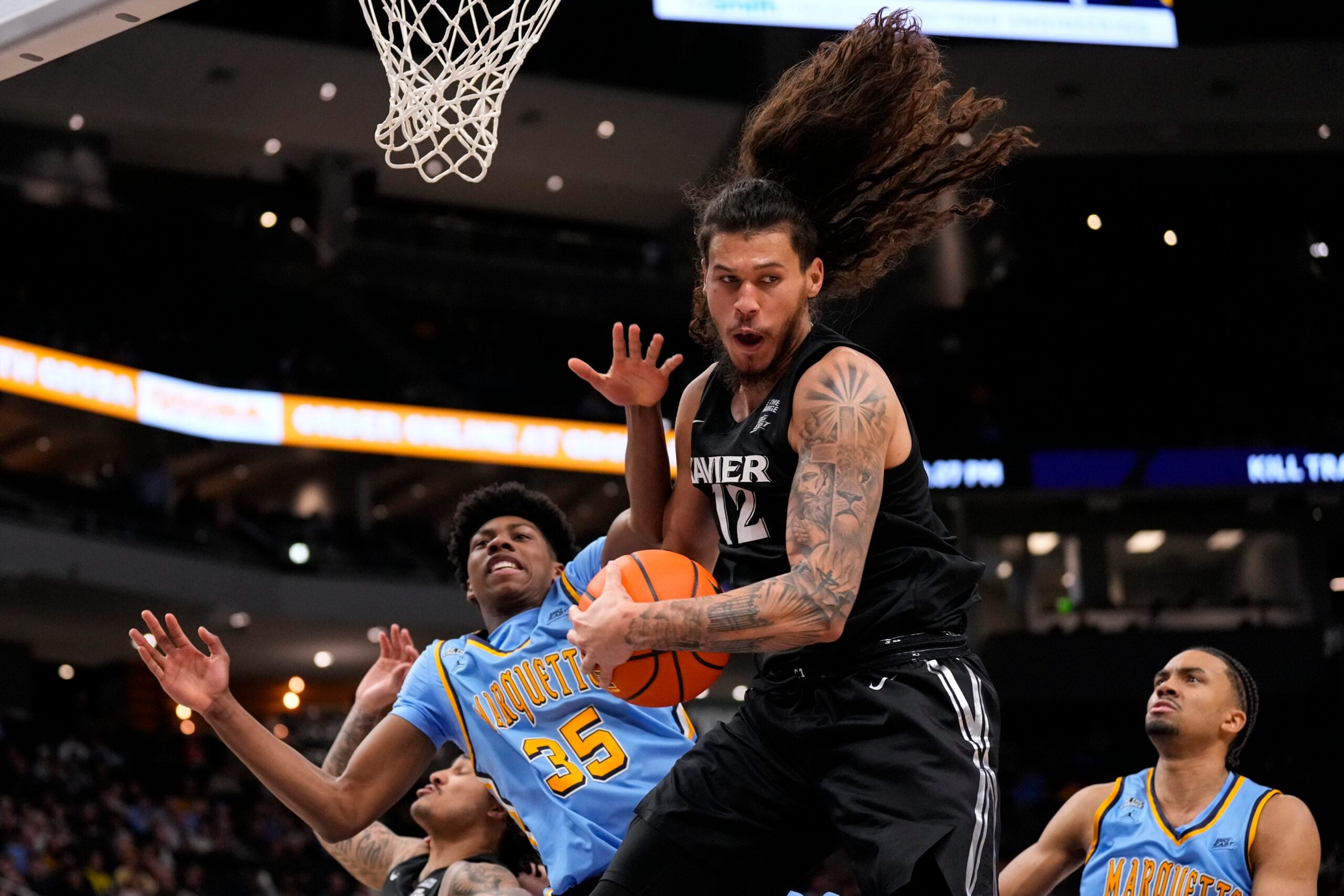 Jan 7, 2026; Milwaukee, Wisconsin, USA;  Xavier Musketeers forward Tre Carroll (12) grabs a rebound in front of Marquette Golden Eagles forward Michael Phillips II (35) during the second half at Fiserv Forum. Mandatory Credit: Jeff Hanisch-Imagn Images