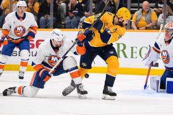 Jan 8, 2026; Nashville, Tennessee, USA; Nashville Predators center Ryan O'Reilly (90) and New York Islanders defenseman Adam Pelech (3) battle for the puck during the third period at Bridgestone Arena. Mandatory Credit: Steve Roberts-Imagn Images