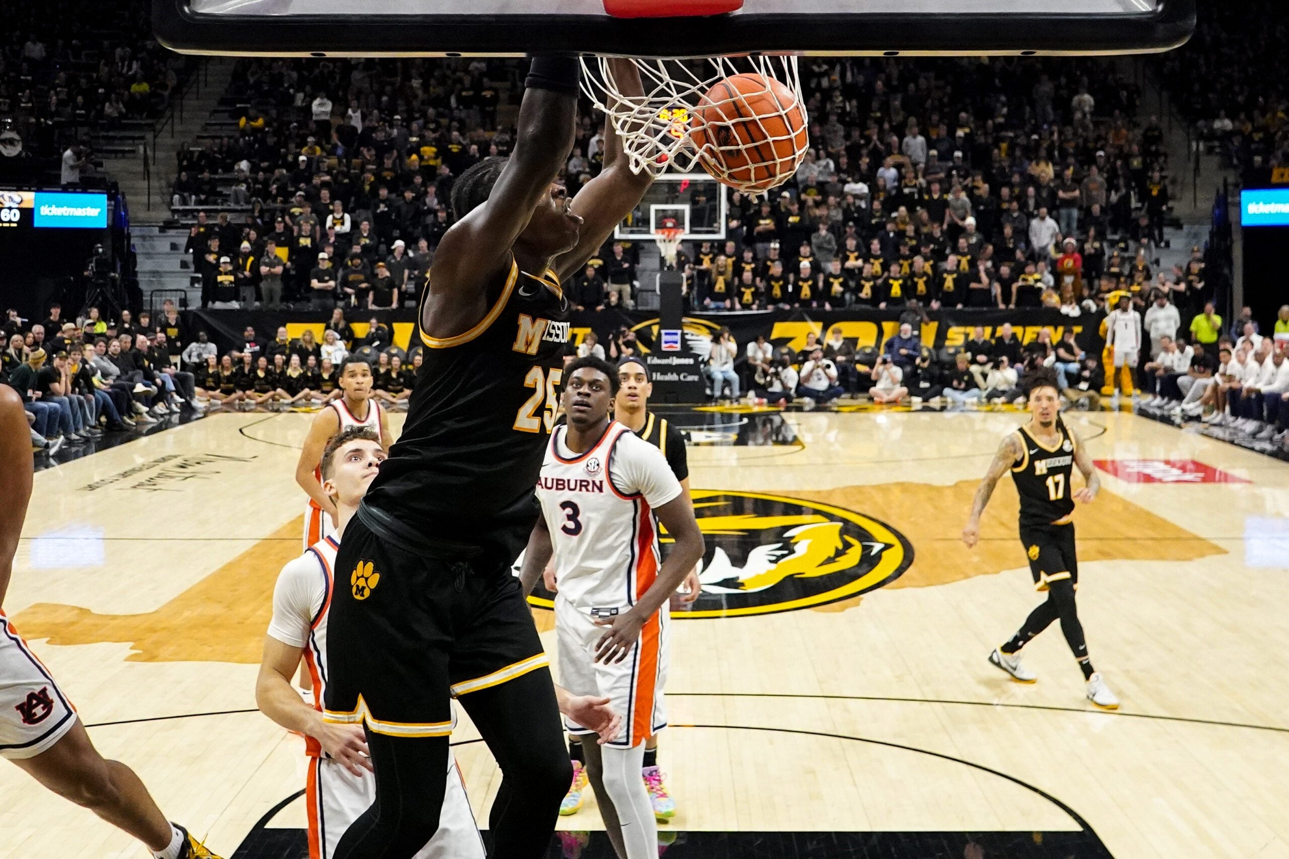 Jan 14, 2026; Columbia, Missouri, USA; Missouri Tigers guard Mark Mitchell (25) dunks he ball as Auburn Tigers forward Keshawn Murphy (3) looks on during the second half of the game at Mizzou Arena. Mandatory Credit: Denny Medley-Imagn Images