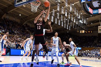Jan 26, 2026; Durham, North Carolina, USA; Louisville Cardinals center Sananda Fru (13) lays the ball up in front of Duke Blue Devils center Patrick Ngongba II (21) during the first half at Cameron Indoor Stadium. Mandatory Credit: Rob Kinnan-Imagn Images