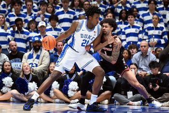 Jan 26, 2026; Durham, North Carolina, USA; Duke Blue Devils center Patrick Ngongba II (21) drives to the basket as Louisville Cardinals guard J'Vonne Hadley (1) defends during the first half at Cameron Indoor Stadium. Mandatory Credit: Rob Kinnan-Imagn Images