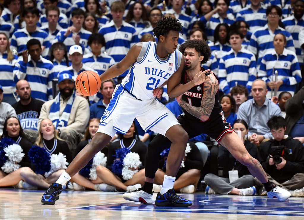 Jan 26, 2026; Durham, North Carolina, USA; Duke Blue Devils center Patrick Ngongba II (21) drives to the basket as Louisville Cardinals guard J'Vonne Hadley (1) defends during the first half at Cameron Indoor Stadium. Mandatory Credit: Rob Kinnan-Imagn Images