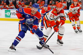Jan 26, 2026; Edmonton, Alberta, CAN; Edmonton Oilers forward Connor McDavid (97) and Anaheim Ducks defensemen Jacob Trouba (65) look for a loose puck during the first period at Rogers Place. Mandatory Credit: Perry Nelson-Imagn Images