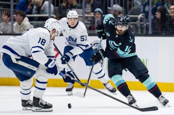 Jan 29, 2026; Seattle, Washington, USA; Seattle Kraken forward Matty Beniers (10) skates against 	 defenseman Chris Tanev (8) during the second period at Climate Pledge Arena. Mandatory Credit: Stephen Brashear-Imagn Images