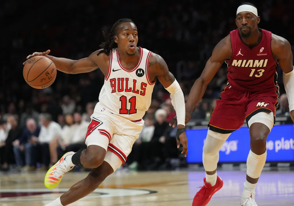 Jan 31, 2026; Miami, Florida, USA; Chicago Bulls guard Ayo Dosunmu (11) drives to the basket as Miami Heat center Bam Adebayo (13) defends during the first half at Kaseya Center. Mandatory Credit: Jim Rassol-Imagn Images